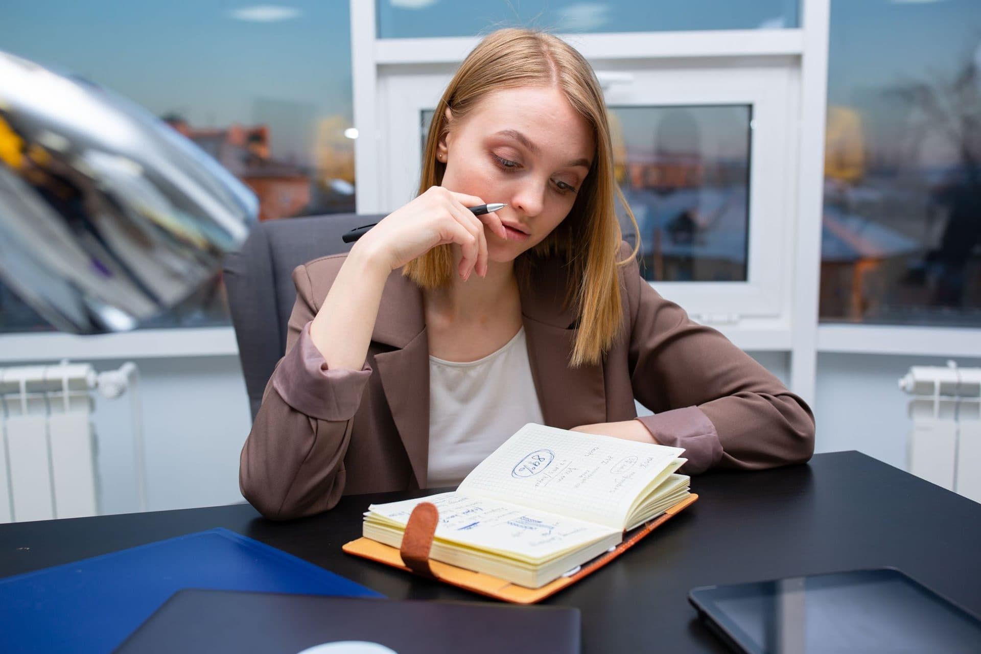 A woman at her desk thinking over her options in a notebook