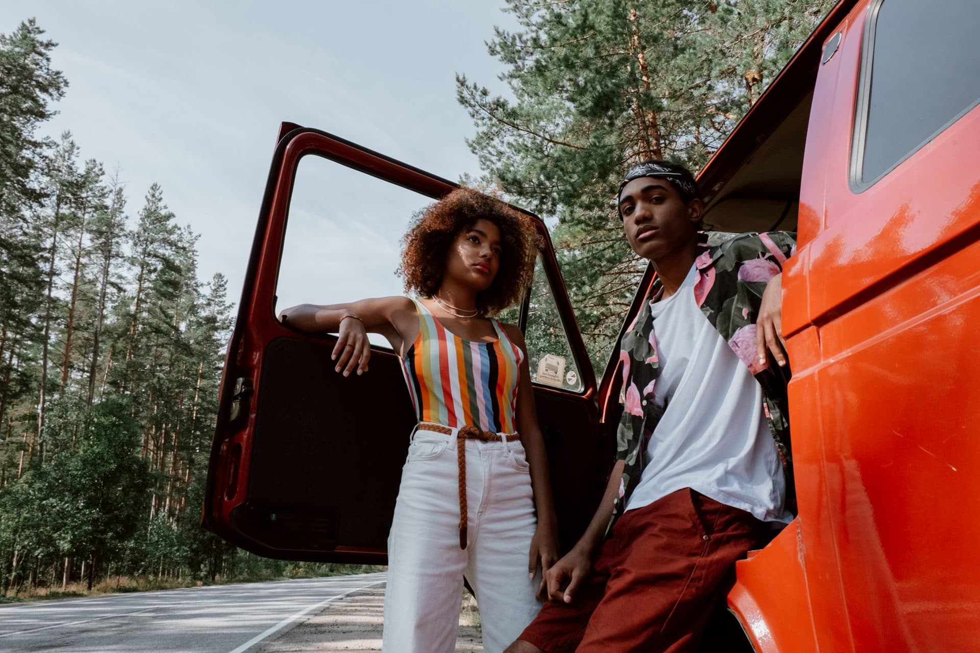 A couple leaning on their van beside a forest road