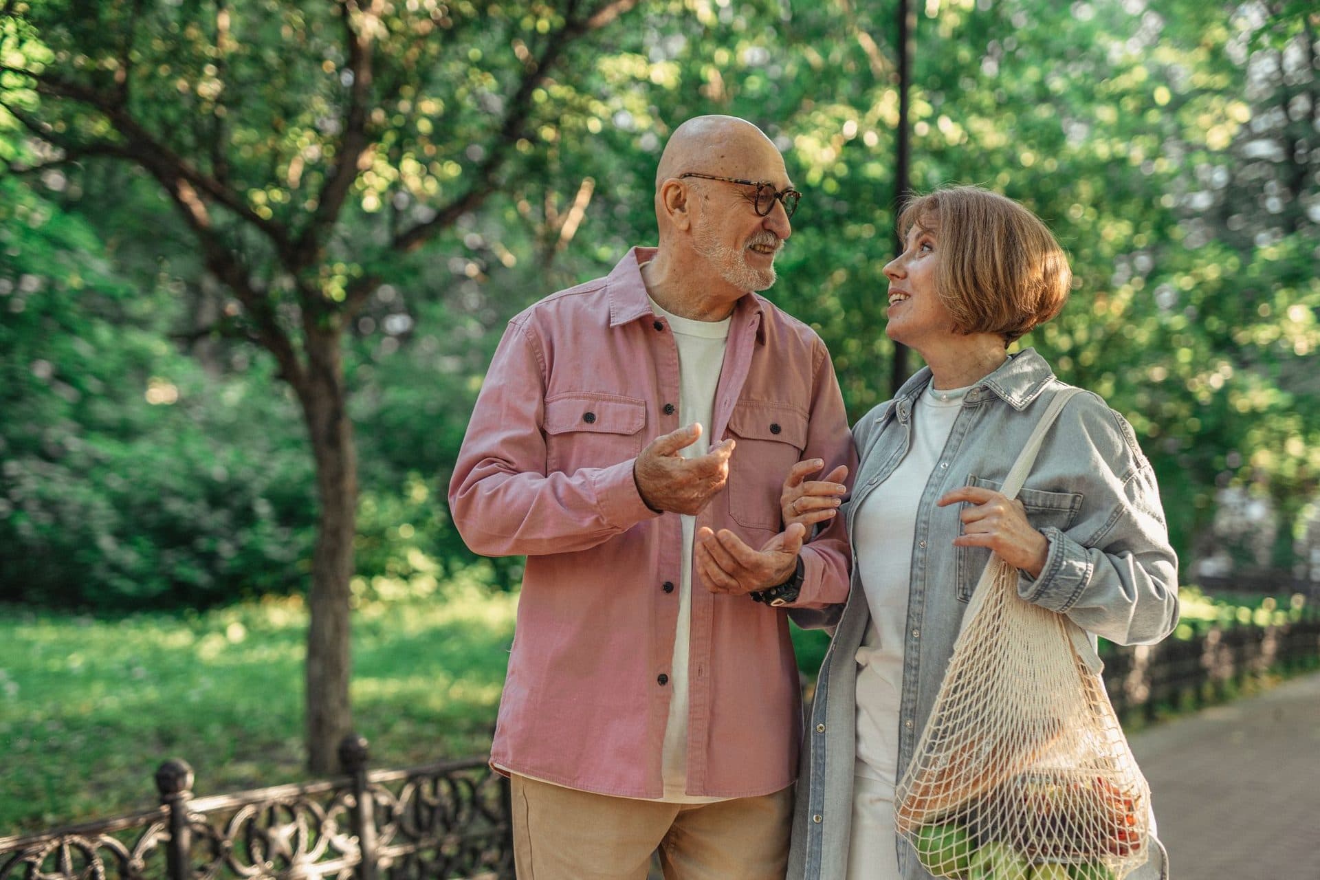 An older couple chatting on a walk through the park