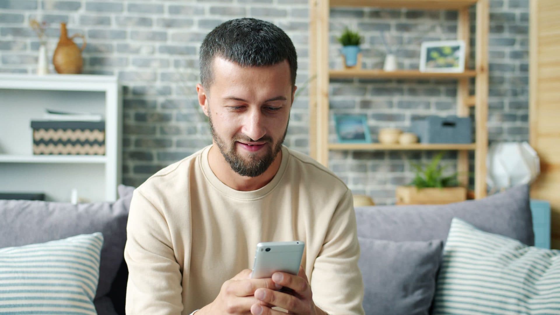 A man on his sofa answering questions on his phone