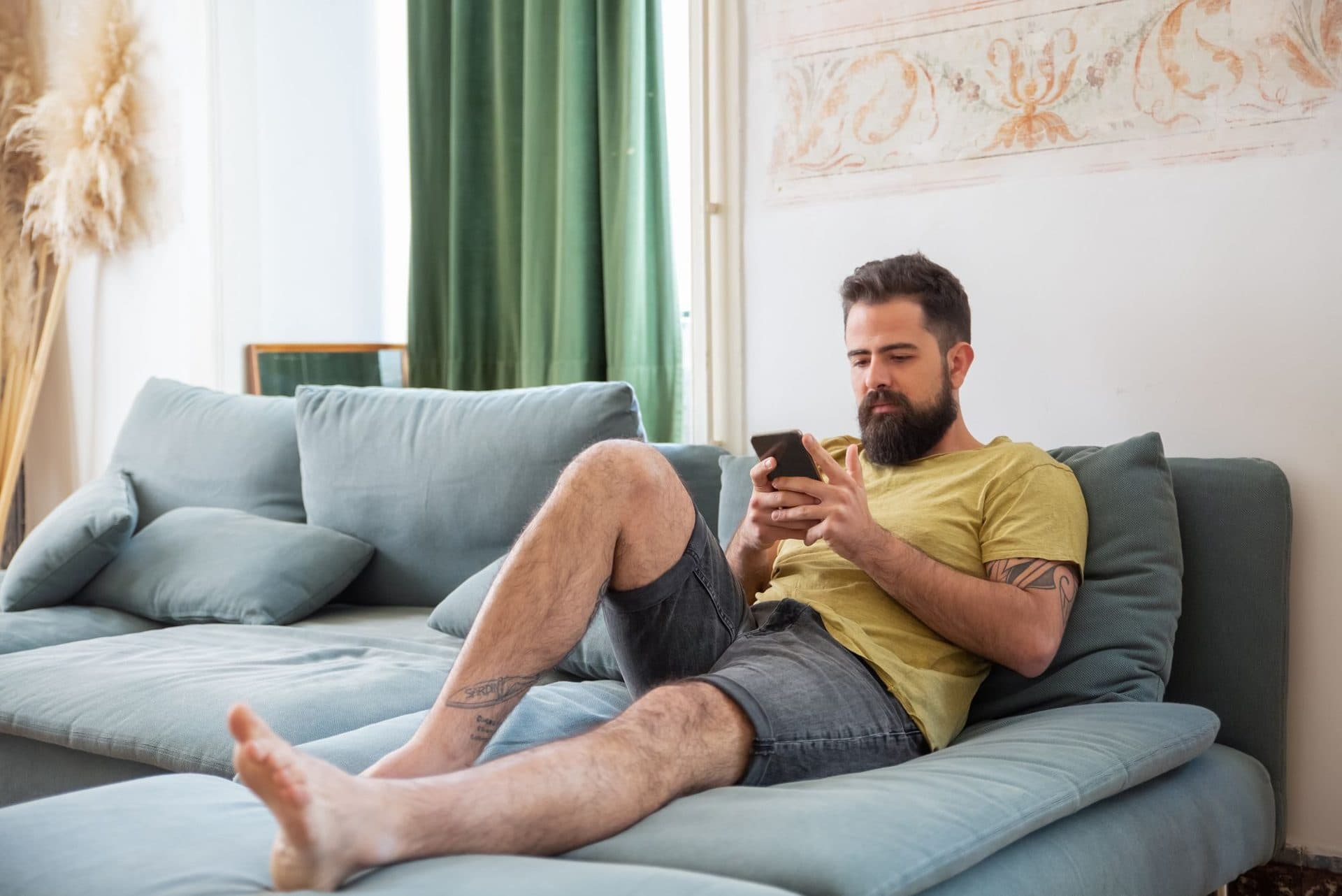 A man stretched out on the sofa using his phone