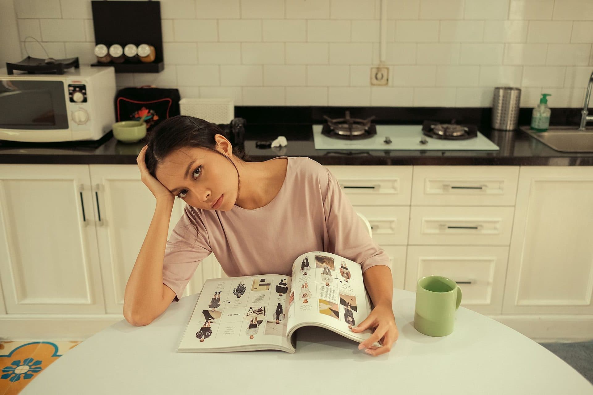 A woman at her kitchen table looking tired over the paperwork