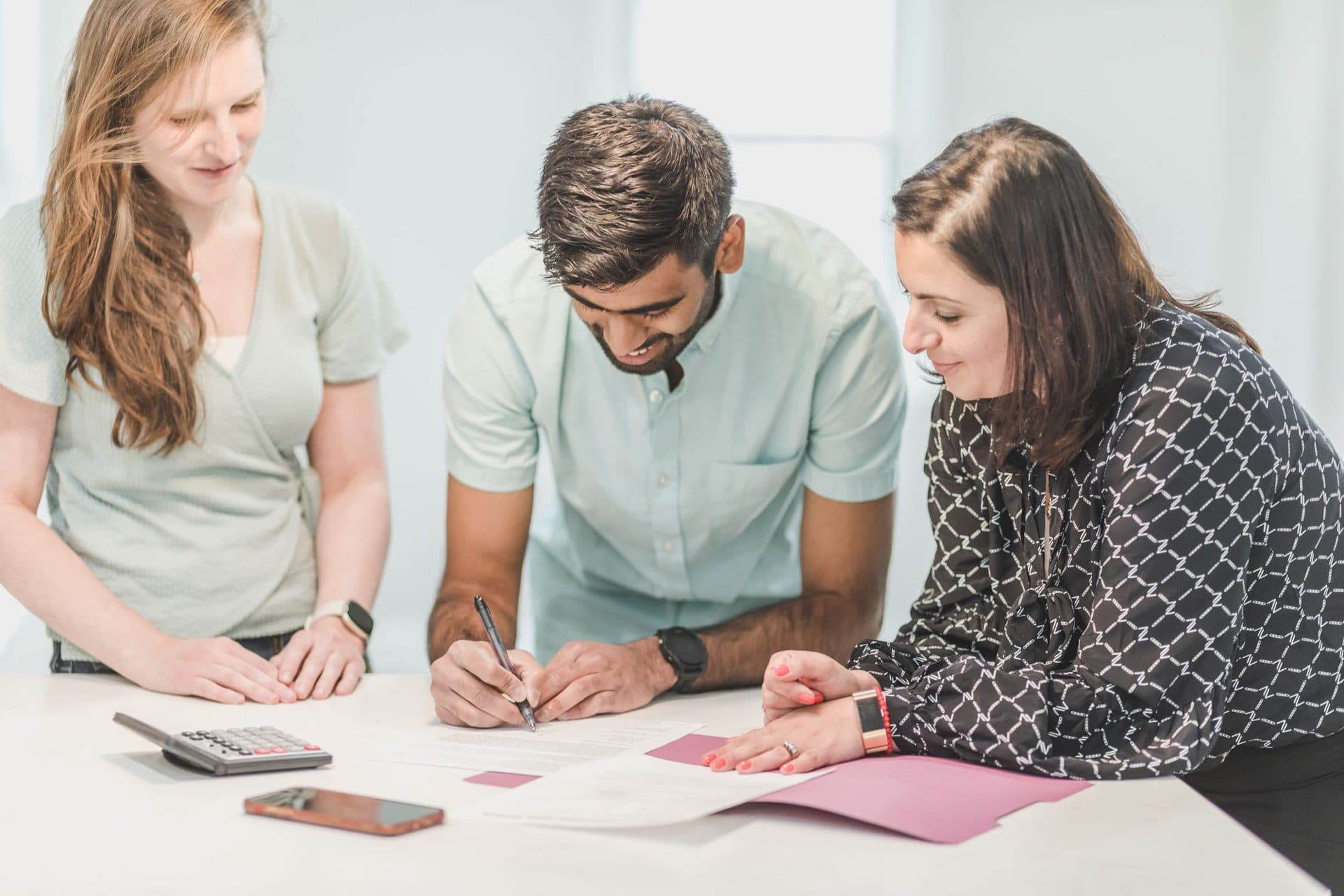 Three people working through household paperwork at a table